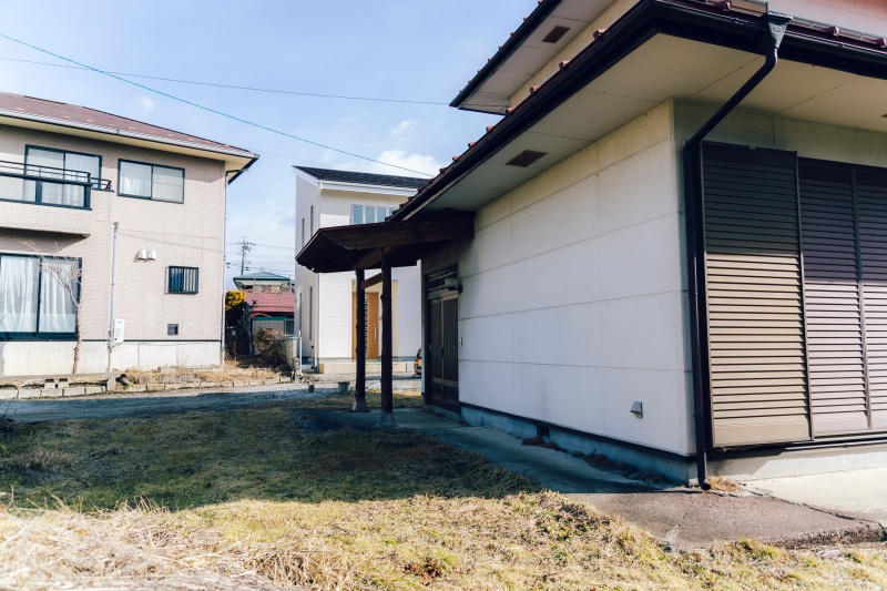 2-story residential building with many rooms on a south-facing open plot adjacent to a national highway. Suitable for dual-family housing or private lodging use.